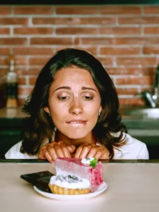 A woman staring at a plate of pastry and other sweet treats on the counter.