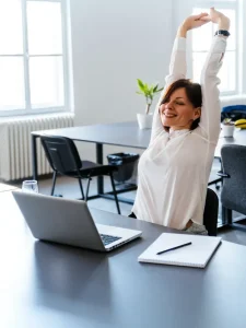 A woman stretching her hands at the desk.
